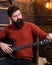 Rock musician with brutal look posing with instrument. Bearded man tuning electric guitar. Man with stylish beard and
