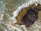 Rock in the ocean, with a beach and sand. Top view, waves, natural texture