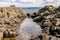 A rock pool with water and a ship on the sea.