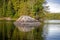 A Rock Stands Guard Over A Small Forested Island