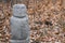 Rock statue of human on orange leaves in autumn forest background