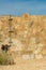 Rock and stone surface on a wild west style adobe building made with metal poles and dirt near base and dark blue sky