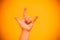 Rock symbol, hand gesture. Cool, party, respect, communication hand gesture. Children`s hand on a bright yellow background. Goat h