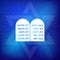 Rock of ten commandments with Hebrew alphabet on blue background