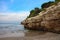 Rock with trees on the sandy beach of Salou against the blue sky. Spain