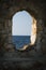Rock wall with a window hole to the blue quiet Mediterranean Sea, in Chania, Crete, Greek Islands