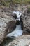 Rock wedged between two rock faces with water rushing around it