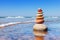 Rock zen pyramid of colorful pebbles standing in the water on the background of the sea. Concept of balance, harmony and