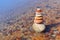 Rock zen pyramid of colorful pebbles standing in the water on the background of the sea. Concept of balance, harmony and