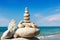 Rock zen of white stones, shells and coral on a background of the summer sea and blue sky