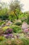 Rockery in the garden with stones and variety of different flowers and plants, nature landscape, vertical background