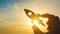 Rocket in the hand of a businessman against the sunset sky. Concept business idea, to start, success and achievement