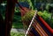 Rocking chair, hammock with wooden support among the trees in the garden. view of naked hairy white legs of a rocking man, striped