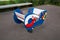 Rocking chair on metal springs in the form of a boat with an anchor and a lifebuoy of blue, white color on a clear sunny day.