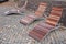 Rocking chair on the pavement under the trees in the square. wooden deck chairs made of tropical wood for one person in the park.