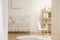 Rocking horse on rug in white kid`s bedroom interior with rabbit poster above cradle