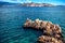 Rocks on cliffs and waves in the ocean, seen from a beach. Calm water, clear sky and waves on a sunny summer day