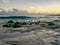 Rocks covered with algae on eroded beach at sunset