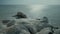 Rocks covered with ice on beach of tranquil shiny ocean