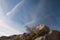 Rocks in the foreground and contrails of airplanes in the sky.