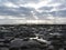 Rocks lunar landscape sea with giants cumulonimbus clouds in the sky and cargo ships at the horizon . Tuscany, Italy