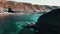 Rocks off the ocean coast line with turquoise water and dramatic cliffs Aerial view.