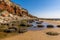 Rocks and rock pools at the base of the white, red and orange stratified cliffs at Old Hunstanton, Norfolk, UK