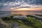 Rocks with seaweeds against a colorful sky,