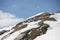 Rocks and snow with blurred ski-lift cable car and mountain range.