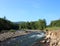 The rocky bank of a small turbulent river flowing down from the mountains through the coniferous forest