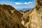 Rocky Barren Cliffs Contrast With Snow Capped Mountains In The Distance