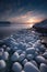 A rocky beach covered in snow at sunset. Generative AI image.