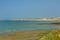 rocky beach with green seaweed and a village in the background along Opal cost of the North sea in France