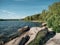 Rocky beach of the lake in Russian Urals. Edge of the water lake with sand and stones and trees on the background