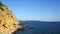 Rocky beach with small sail boat in the distance