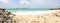 Rocky beach view at Caribbean sea coast, with light blue sky and white clouds. Sunny beach landscape with rocks and huge foamy