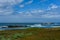 Rocky blue Pacific ocean coastal landscape with waves breaking against the rocks under a dramatic partly cloudy sky