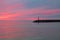 Rocky Breakwater With Red Sky And Water