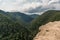 Rocky cliff, clouds and mountains