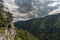 Rocky cliff, clouds and mountains