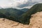 Rocky cliff, clouds and mountains