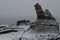 Rocky cliff on the coast under a snowfall.