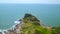 Rocky cliff on green island in blue sea and sailing ship on skyline aerial landscape. Drone view cliff on rocky shore of