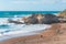 Rocky cliffs, sandy beach, and people enjoying beautiful sunny day. Montana de Oro State park, Los Osos, California Central Coast