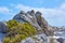 A rocky coast with green lichens and waves rushing through shores hitting. An ocean with a rocky coast. View of a rocky