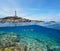 Rocky coast with a lighthouse and fish underwater, split view half above and below water surface