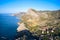 The rocky coast of the sea with a settlement and a mountain road. Shooting from a drone