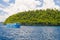 Rocky coastline of island spotted by islets and covered by dense lush green jungle in the colorful sea of the remote Togean Island
