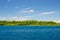 Rocky coastline of island spotted by islets and covered by dense lush green jungle in the colorful sea of the remote Togean Island