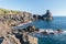 Rocky coastline of lava cliff near Acireale Sicily, with a watchtower in the background